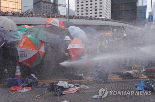 경찰의 물대포를 우산으로 막고있는 홍콩 시민들 [사진 = 연합뉴스]